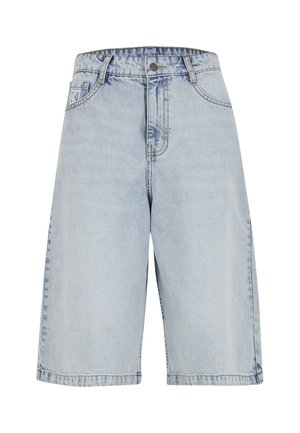 Helehallid teksapüksid lõdva lõikega, millel on vöökoht, esi taskud ja nähtavad õmblused servadel.