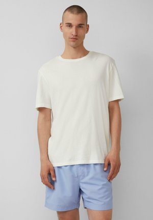 Witte katoenen T-shirt met korte mouwen, gecombineerd met lichtblauwe shorts. Het T-shirt heeft een ronde hals en een relaxed fit.