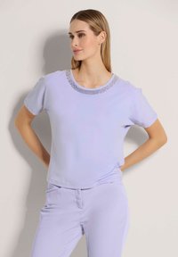 Lila korte mouwen top met een ronde hals en decoratieve kralenaccenten rondom de halslijn. Zacht, soepel materiaal met een ontspannen pasvorm.