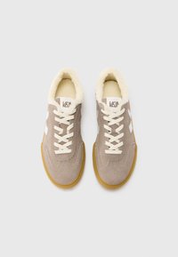 Bež antilopske tenisice s kremastim krznom sa unutarnje strane, bijelim detaljima i bež pertlama. Klasični dizajn ima gumeni potplat boje trske i prošivene detalje.