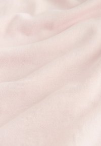 Tissu en coton rose pâle et doux avec une texture côtelée fine et des plis délicats, montrant un détail en gros plan de la surface du matériau.
