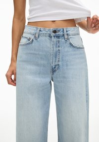 Hellblaue hoch geschnittene Jeans mit lockerer Passform, ausgestattet mit einem Fünf-Taschen-Design und dezenten Stickdetails am Bund und den Taschen.