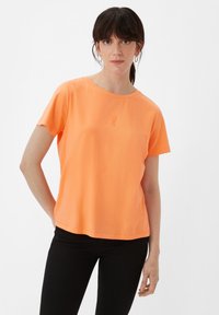 Oranges Kurzarm-T-Shirt aus weichem Material mit Rundhalsausschnitt, das einen dezenten Logo-Druck auf der Brust und einen lockeren Schnitt hat.
