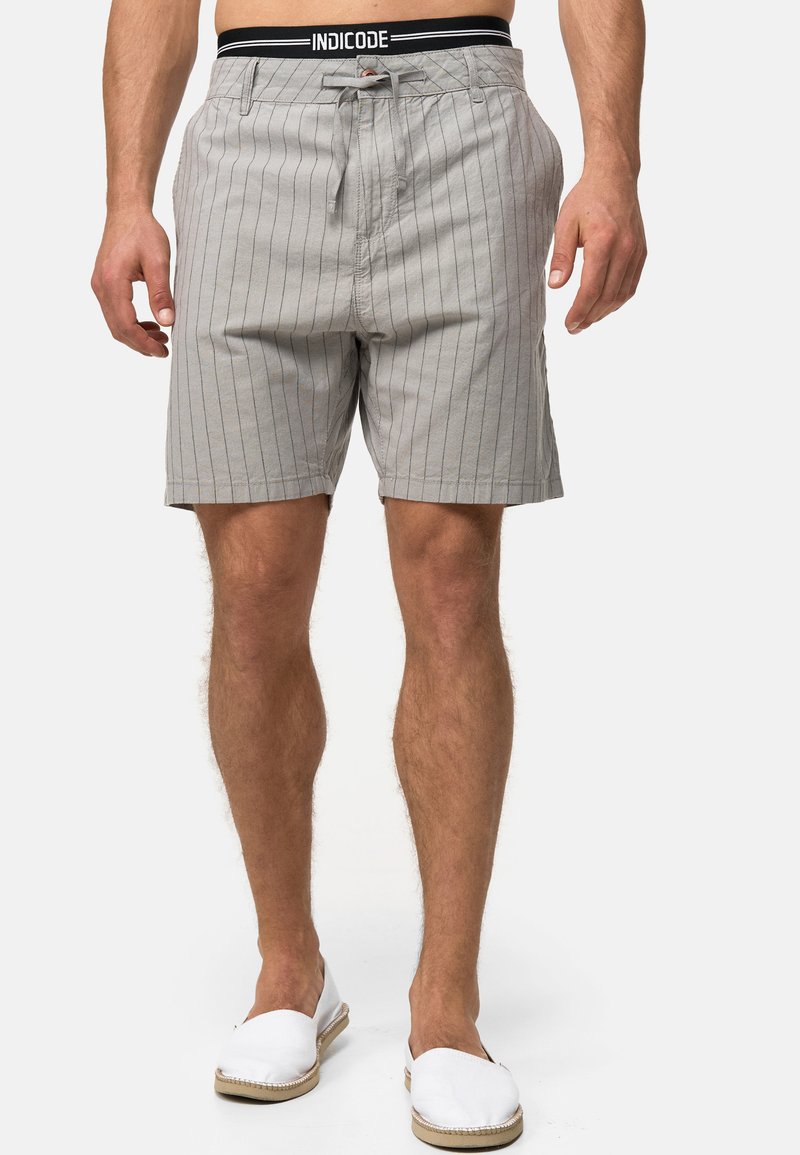 Grå stribede shorts med en sort elastisk talje, der har en justerbar snor og sidelommer. Fremstillet af letvægtsstof.