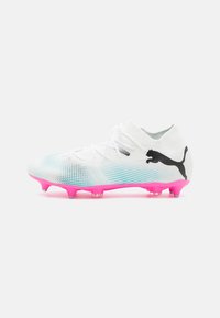 Scarpe da calcio bianche con superficie texturizzata, dettagli in gradi blu, suola traslucida rosa e logo Puma nero sul lato.