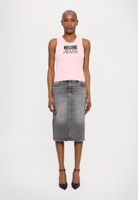 Top de malha riscada rosa claro com gráfico "MOSCHINO JEANS", combinado com uma saia midi de jeans cinza escuro e sapatos de salto preto de bico fino.