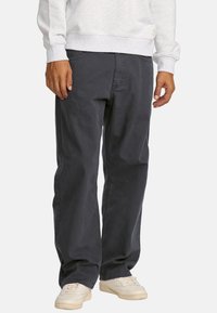 Dark gray, straight-leg pants made of cotton, featuring a relaxed fit, side pockets, and subtle stitching details. Worn with white sneakers.