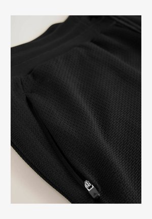 Čierne športové šortky s textúrovanou tkaninou, zipsom na vrecku a elastickým pásom. Navrhnuté pre pohodlie a flexibilitu.