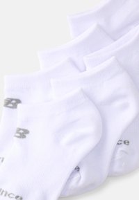 Chaussettes blanches en coton jusqu'à la cheville avec côtes, avec un petit logo gris. Cinq paires disposées pour montrer la forme et les détails de conception.