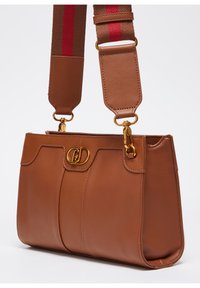 Borsa a mano in pelle marrone con forma strutturata, dotata di una chiusura in metallo dorato e un tracolla staccabile con accenti rossi e marroni.