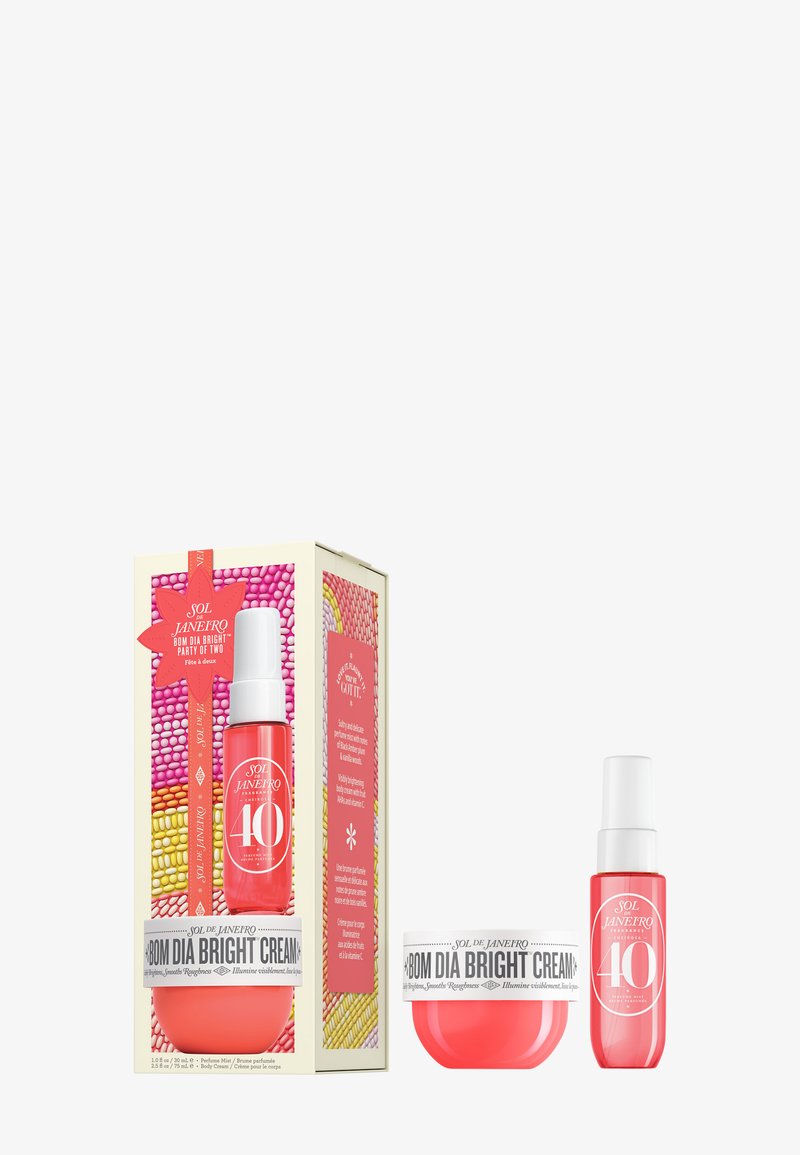 Lys rosa krem og serum i klare beholdere, med hvitt og fargerikt emballasje med tekst og en dekorativ etikett.
