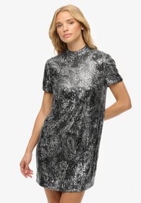 Vestido de manga corta en negro y lentejuelas plateadas, con textura acanalada y un diseño estampado con tonos y brillos variados.