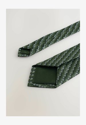 Zaļā kaklasaite ar teksturētu rakstu, kurā ir ģeometriskas līnijas balto un sudraba akcentu krāsā. Izgatavota no gludas auduma, ar smailu galu un plašu asmeni.