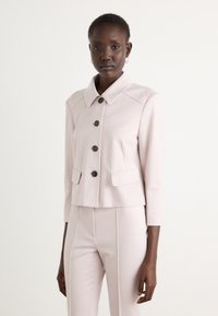 Lichtroze cropped jack met een grote kraag, zwarte knopen en twee voorkezen. Gladde textuur en getailleerde pasvorm, gecombineerd met bijpassende broek.