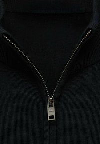 Schwarzer Zip-Pullover aus strukturiertem Strickstoff, mit einem silbernen Reißverschluss und hohem Kragen. Der Zipper-Anhänger zeigt den Markennamen.