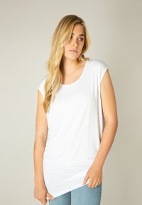Witte korte mouwen top van zachte stof met een relaxte pasvorm en een ronde hals, die lichtjes aan de zijkanten valt, gecombineerd met lichtblauwe jeans.