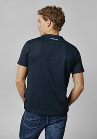 Donkerblauwe t-shirt van een zachte stof, met korte mouwen en een ronde halslijn. De merknaam "Pepe Jeans" is op de achterkant gedrukt.