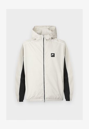 Jasnoszara wiatrówka Nike Air na zamek z kapturem i czarnymi panelami wzdłuż wewnętrznych części rękawów.