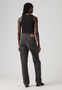 Zwarte tanktop gecombineerd met grijze denim jeans met hoge taille, voorzien van een leren patch op de achterkant van de tailleband en een losse pasvorm.