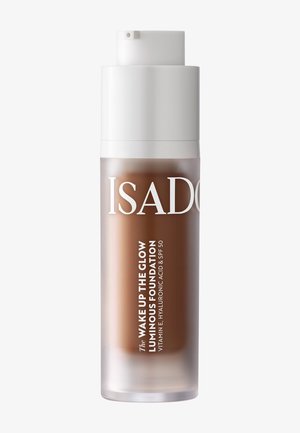 Flacon de fond de teint lumineux IsaDora Wake Up The Glow avec vitamine E, acide hyaluronique et SPF 50 en teinte moyen foncé.