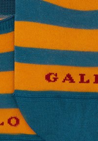 Calzini a righe in arancione e teal. Tessuto misto cotone con texture a coste. "GAL" ricamato in rosso nella parte teal.