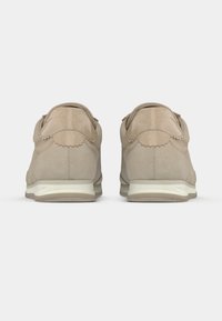 Μπεζ αθλητικά παπούτσια με σουέντ και γυαλιστερό φινίρισμα, που διαθέτουν ανάγλυφη λεπτομέρεια στο πίσω μέρος και υφή στη σόλα.