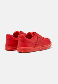 Sneakers rossi in pelle con superficie testurizzata, lacci piatti e suola decorata. Presentano un marchio sul tallone e un design della punta arrotondati.