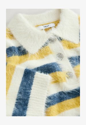 Adītu džemperis baltā, dzeltenā un zilā svītrā, ar apkakles dekoltē un teksturētu audumu, izrotāts ar dārgakmeņiem līdzīgiem pogām.