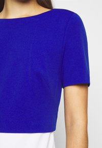 T-shirt z krótkim rękawem w jednolitym niebieskim kolorze, z szerokim okrągłym dekoltem i prostym fasonem z delikatnie teksturowanym wykończeniem.