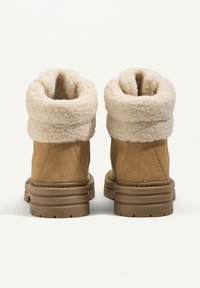 Smeđi antilop čizmi do gležnja s kremastim umetkom od lažne krznene tkanine, sa debelim gumenim potplatom i zaobljenim vrhom za udobnost i toplinu.