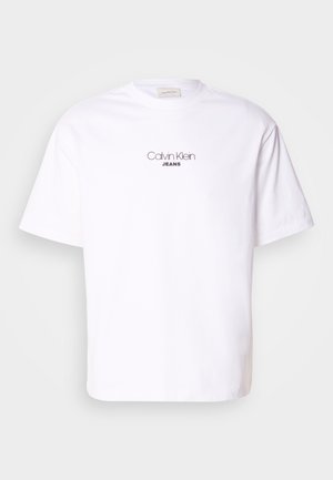 Weißes Baumwoll-T-Shirt mit Rundhalsausschnitt und kurzen Ärmeln. Auf der Vorderseite ist "Calvin Klein" in einer minimalistischen Schrift über "JEANS" abgebildet.