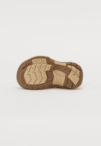 Ruskea kumipohja, jossa on teksturoitu pinta, syvät urat ja kuviot parantuakseen pitoa ja vetovoimaa. Vankka ja kestävä muotoilu.