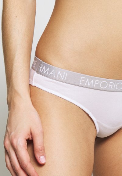 Balta kokvilnas bikini peldkostīms ar gaiši pelēku elastīgu jostasvietu, kurā ir "Emporio Armani" logo. Gluda tekstūra, piestiprināta forma, minimālas pārklājuma stils.