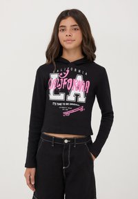 Felpa corta nera con texture a costine. Presenta grafiche bianche e rosa: "CALIFORNIA," "LA," e un design di skate. Maniche lunghe.