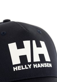 Gorra de béisbol de color navy hecha de textil, con un gran logo blanco "HH" y el texto "HELLY HANSEN" en negrita. Incluye acentos bordados en el ala.