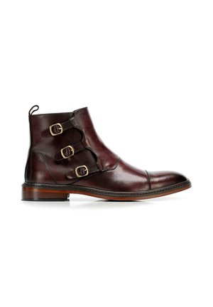 Bottines en cuir bordeaux foncé avec trois boucles dorées, bout arrondi et semelle marron. Présente des coutures le long du bord et une languette à l'arrière.