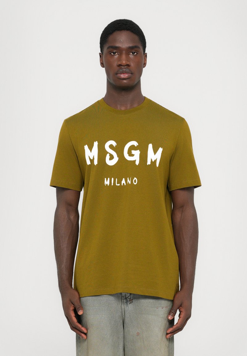 Olivengrønn t-skjorte med fet hvit "MSGM" og "MILANO" tekst, rund halslinning og korte ermer. Laget av et glatt, lett materiale.