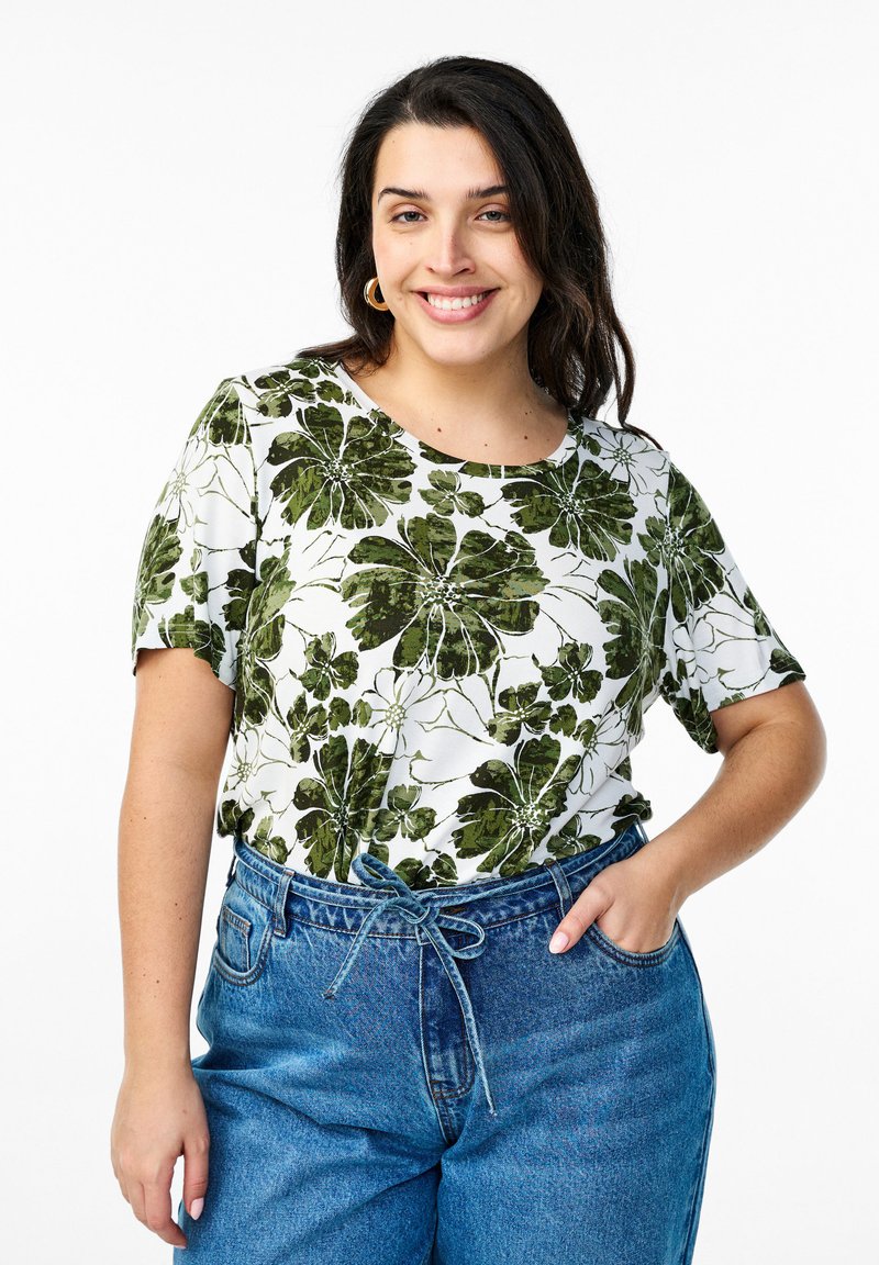 Balta trumpa rankovėmis marškinėlė su žaliais gėlių raštais. Derinama su aukštu juosmeniu mėlynomis džinsinėmis kelnėmis su priekine rišimo detalėmis.