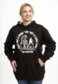 Černá mikina s kapucí má grafický design se skeletonem a žralokem, bílý text s nápisem "JSEM TU NA DOBROU ZÁBAVU, NE NA DLOUHO" a "POP CREATURE."