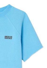 T-shirt en coton bleu clair avec un col rond côtelé et des manches raglan courtes. Logo "AMERICAN VINTAGE" imprimé en noir à l'avant.