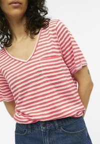 T-shirt à manches courtes en V rayé rose et blanc avec une poche poitrine, fabriqué en tissu doux, associé à un jean bleu.