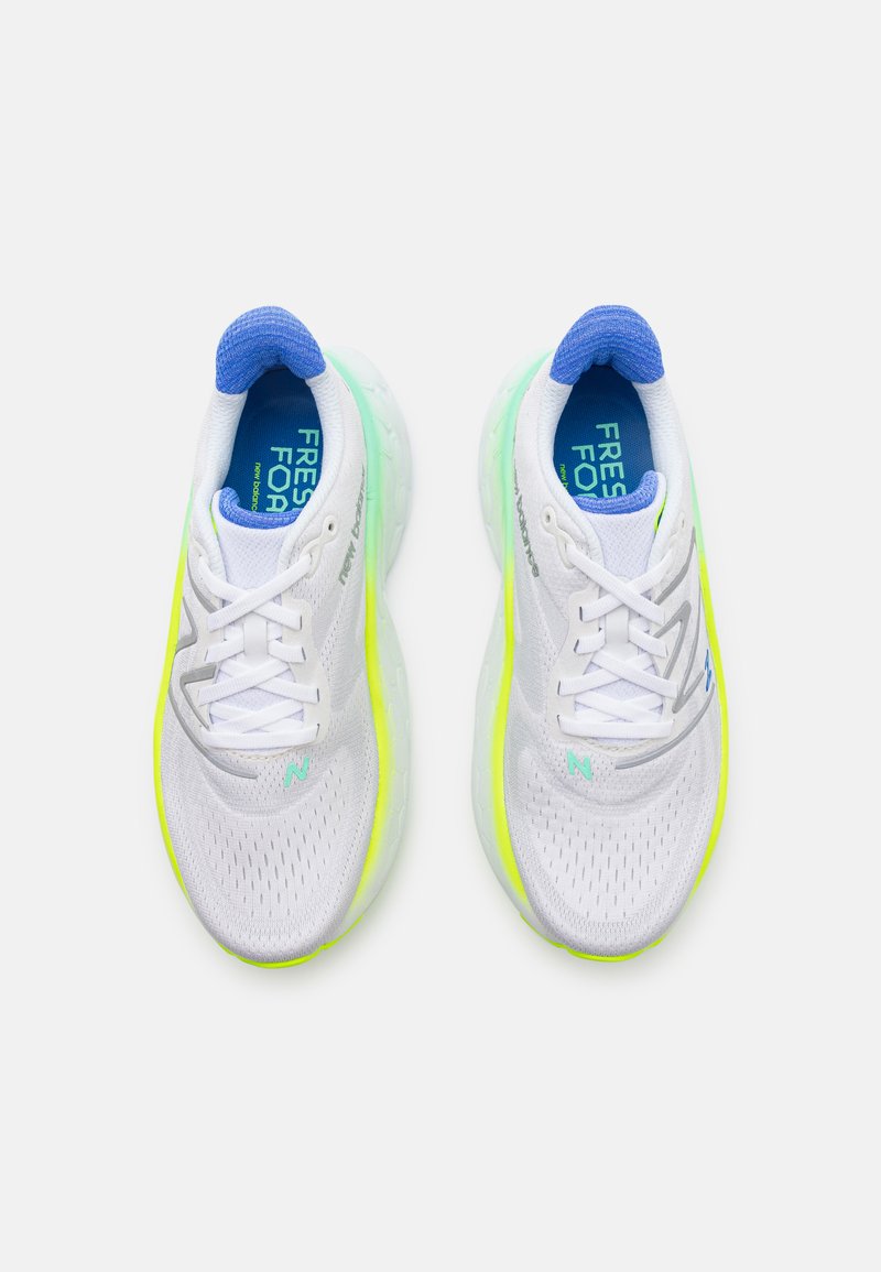 Zapatillas deportivas blancas con parte superior de malla transpirable, acentos en amarillo neón y suela acolchada. Detalle en azul en el cuello y la plantilla.