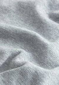 Tissu gris clair côtelé avec une texture douce, présentant de fines lignes verticales et de subtiles variations de teinte sur la surface.