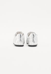 Chaussures métalliques argentées avec une texture lisse, un bout arrondi, un design minimaliste, une semelle noire et sans matériel visible.