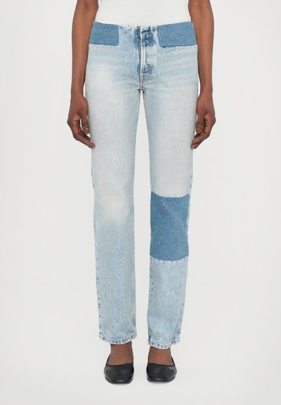 Lichtblauwe denim jeans met een patchworkdesign en donkerblauwe accenten bij de tailleband en knie. Rechstreeks silhouet.
