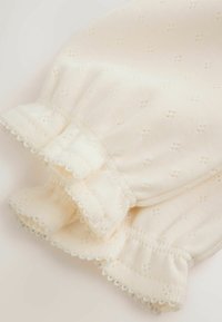 Cream-colored fabric with delicate small holes, featuring elasticized ruffled cuffs and a bow detail.