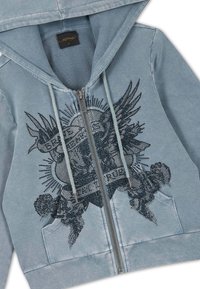 Light blue zip-up hoodie with drawstrings, front pockets, and a black rhinestone design featuring wings and text on the chest.