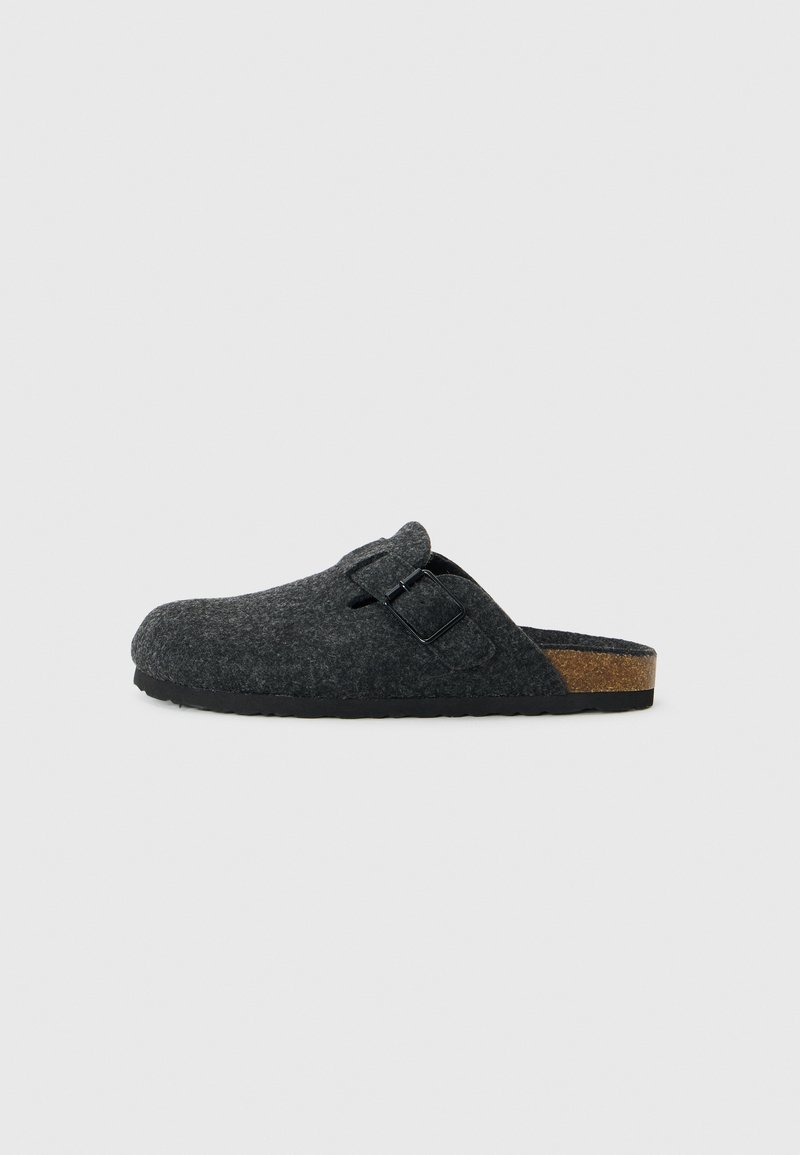 Grå slip-on clog i filt med en buet form, justerbar spenne og naturlig kork såle. Teksturert overflate og gummisåle.