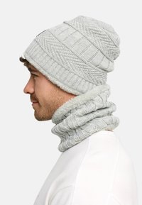 Gray knit beanie with textured patterns and a plush lining, paired with a matching gray knit neck gaiter featuring a ribbed design.
