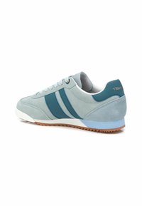 Sneaker in suede blu chiaro con strisce blu scuro, suola bianca e suola in gomma antiscivolo marrone. Design arrotondato con collarino imbottito.